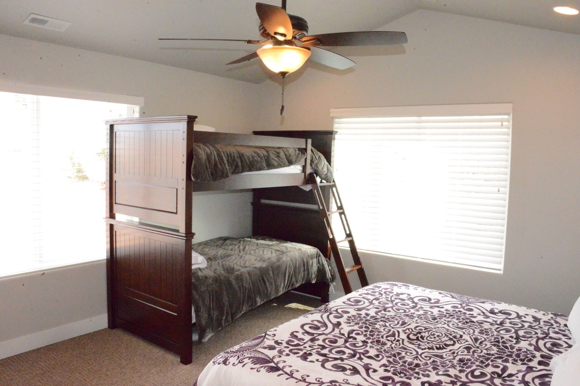 Bright bedroom with a bunk bed, a big bed and two windows