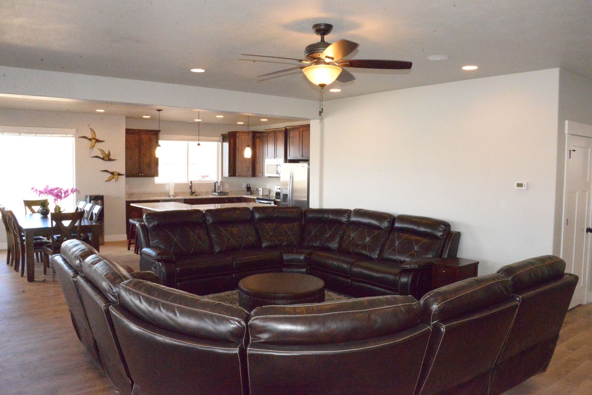 Open great room with two large leather sectionals, dining table and kitchen