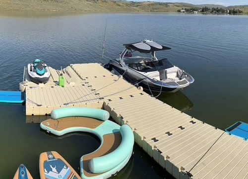 The wake boat, jet ski, paddleboards and floating lounge tied up at the private dock