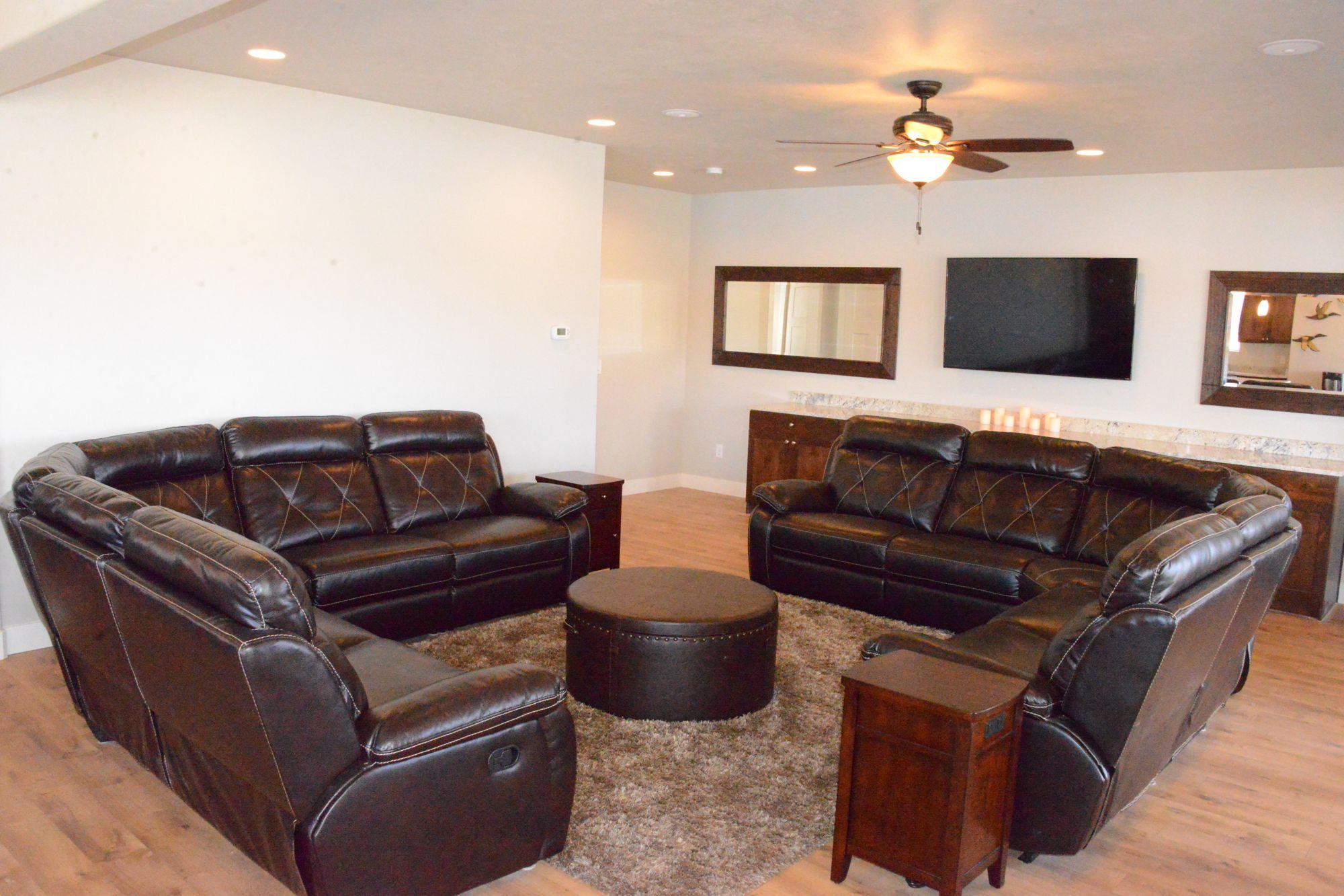 Leather reclining sectionals around a round ottoman in front of the TV