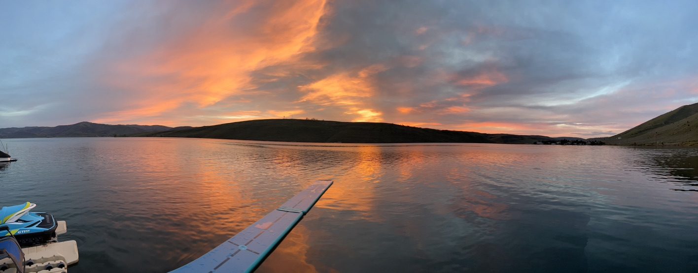 Orange and pink sunset reflected across Scofield Reservoir, seen from the dock with a jet ski alongside