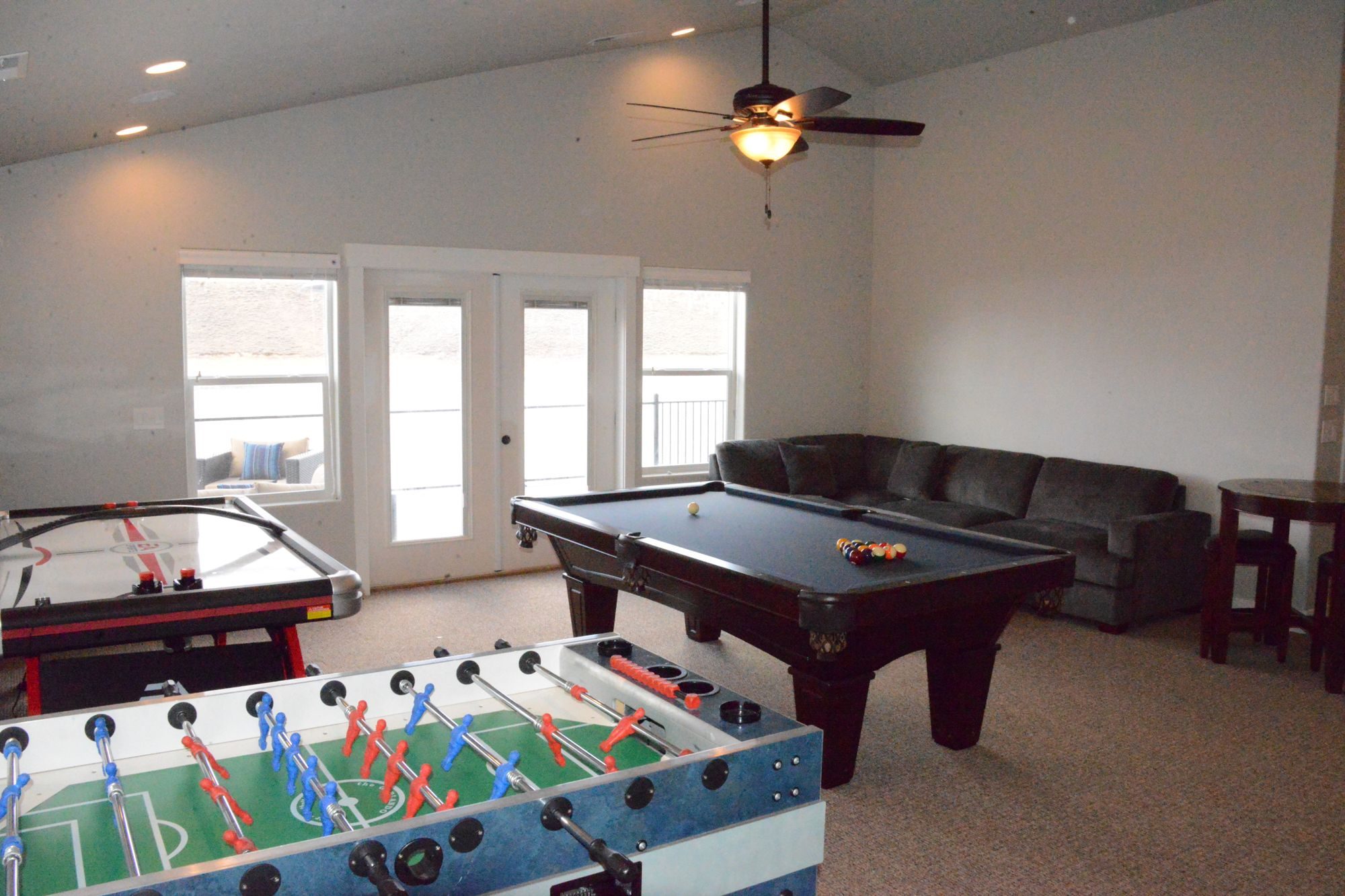 Foosball, air hockey and pool table with the balcony doors behind