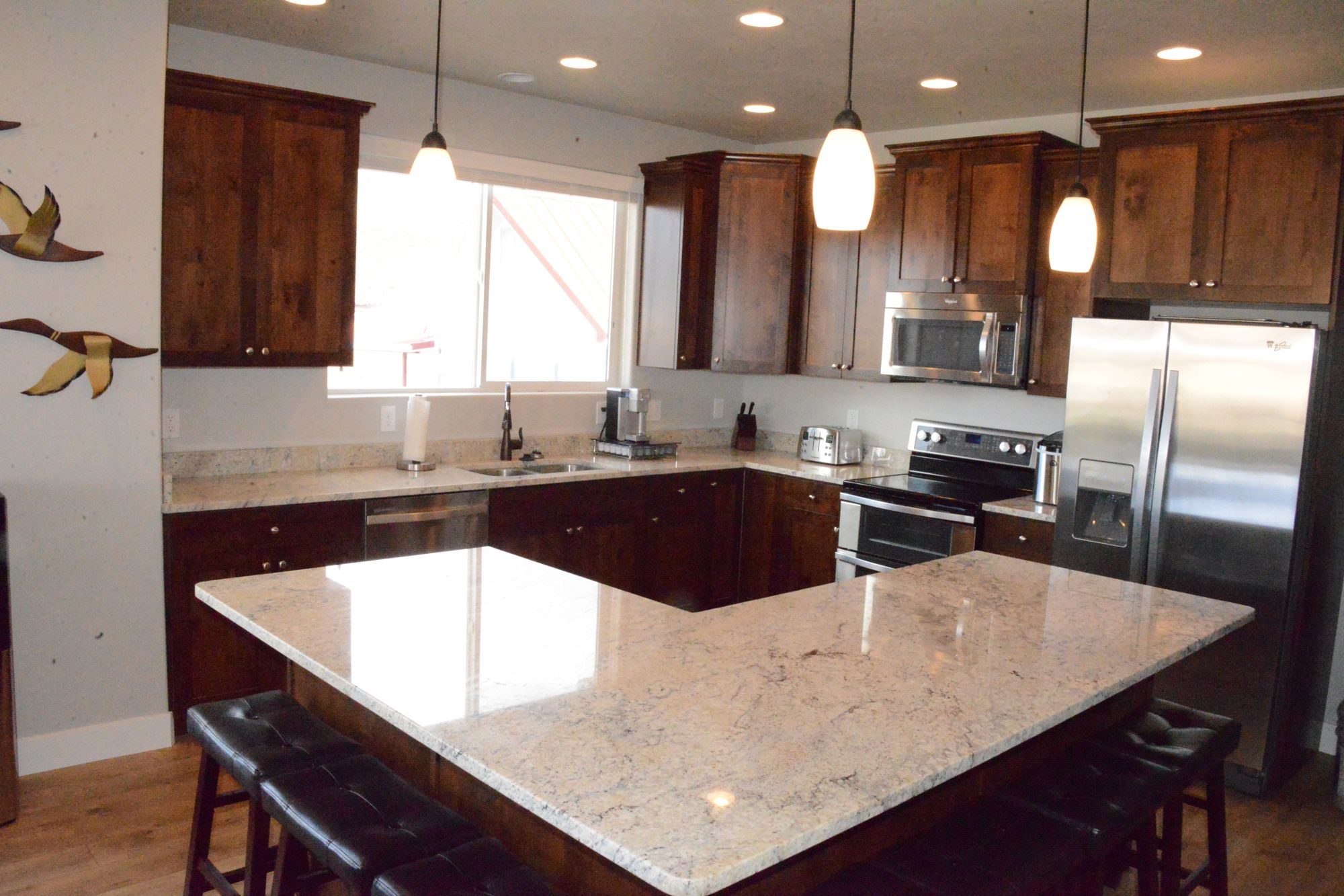 Kitchen with granite island, bar stools and stainless steel appliances